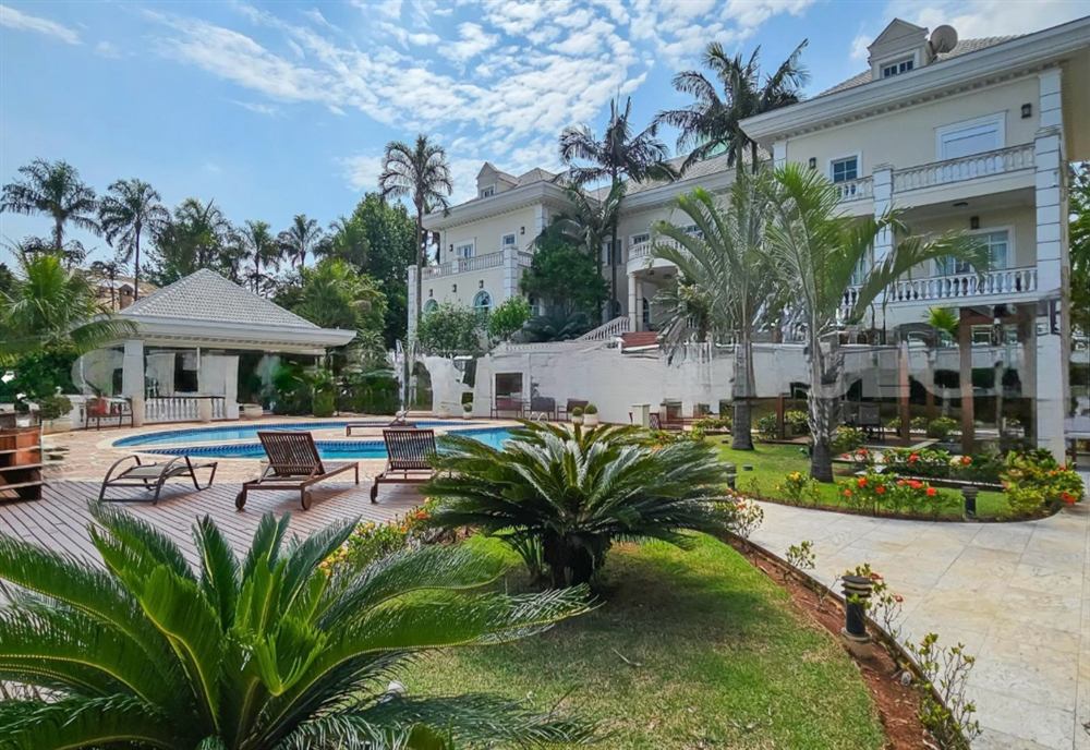 Casa neoclássica com piscina, deck e palmeiras